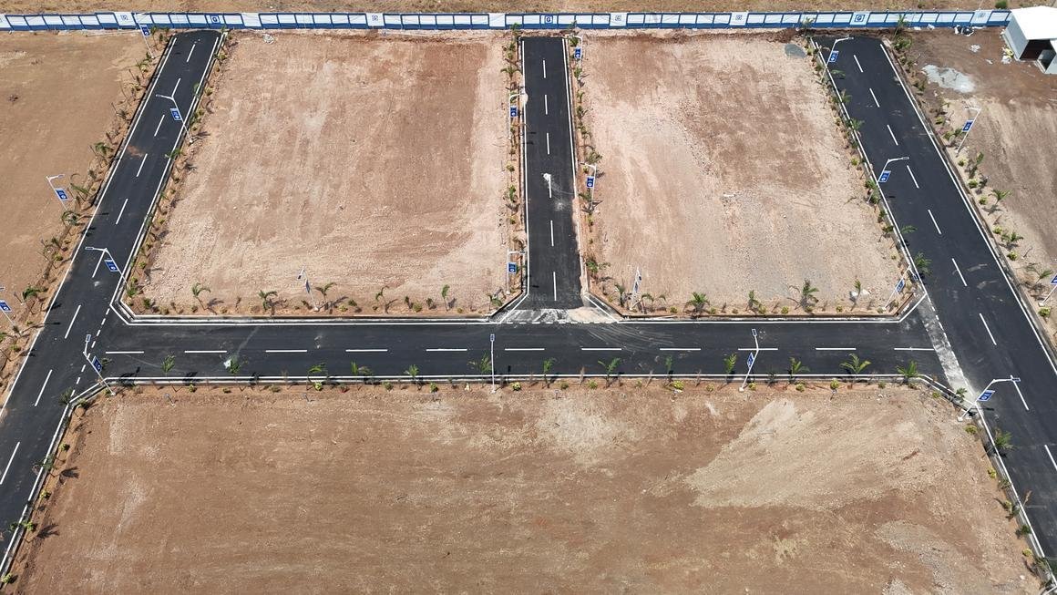 Aerial view of a symmetrical open plot layout with tar roads and compound wall, developed by real estate companies in Hyderabad